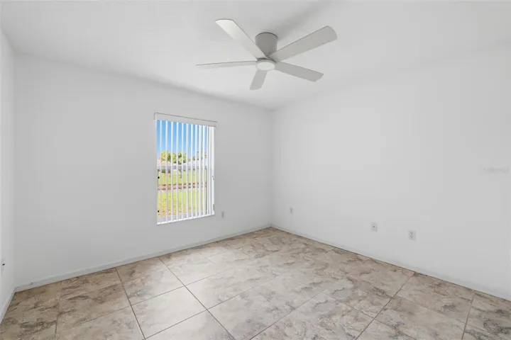 Bright bedroom with large window, ceiling fan, and open, airy feel