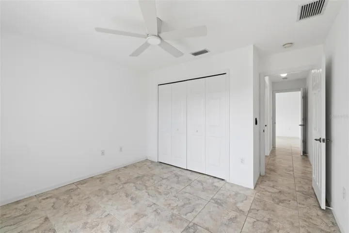 Comfortable bedroom with ceiling fan, neutral walls, and tile flooring throughout