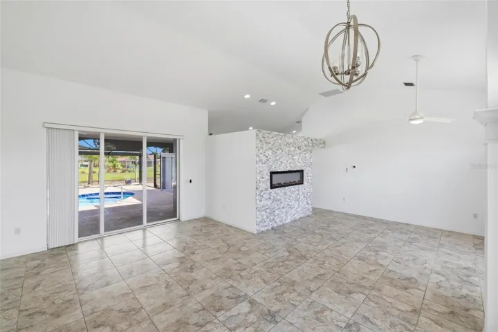 Spacious living area with chandelier, large windows, and light-filled neutral interior