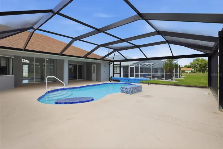 Generous pool deck with panoramic screen enclosure and peaceful backyard setting