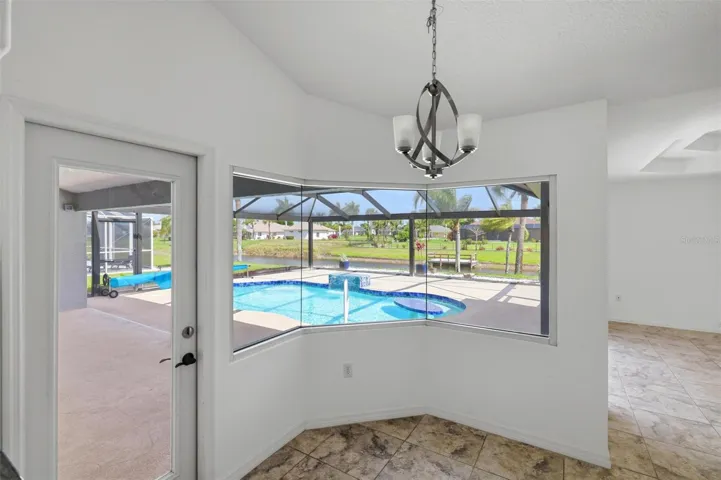 Elegant dining area with chandelier, large windows, and views of the pool
