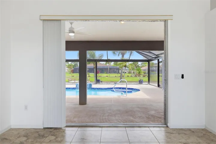 Sliding glass doors leading to extended screened lanai and newly redone 2025 pool