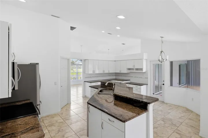 Spacious kitchen with island, dark granite counters, and view into living area
