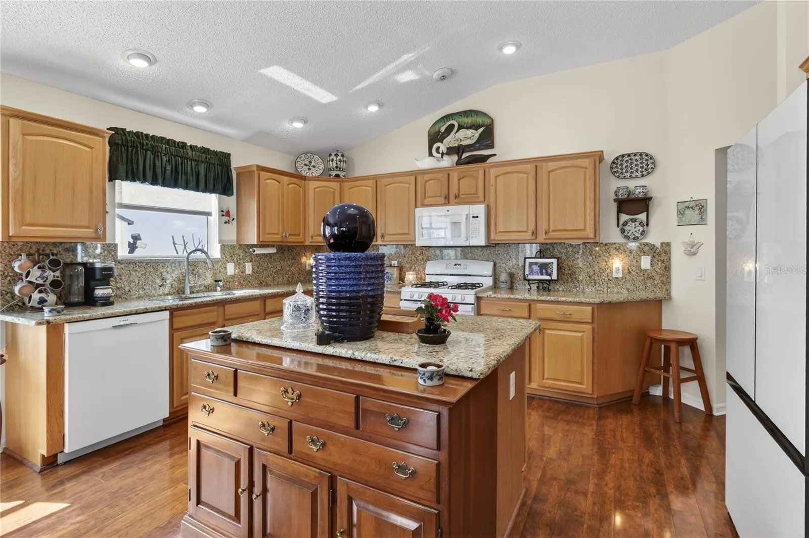 This captivating kitchen is a true chef's paradise, boasting beautifully crafted warm wood cabinets, complemented by stunning, durable granite countertops that provide both an exquisite aesthetic and a practical workspace for culinary creations. S