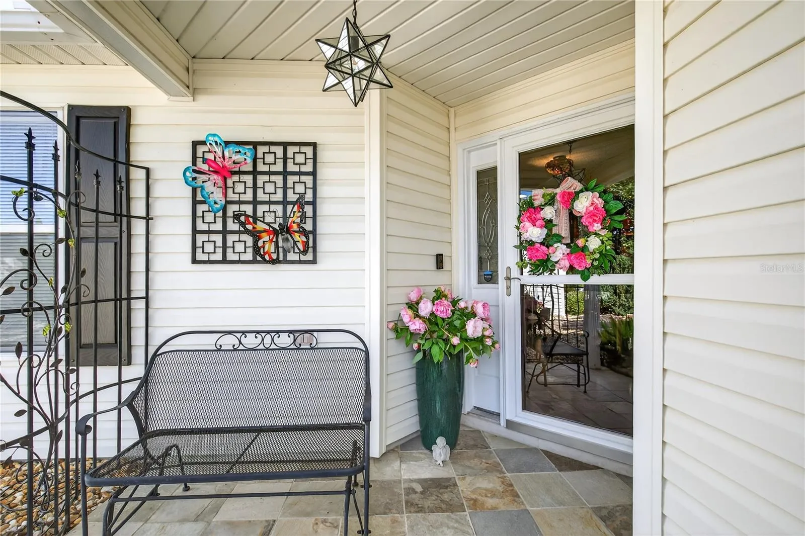 The welcoming front entrance is beautifully enhanced with a durable slate tile floor, complemented by a functional glass storm door that allows for ample natural light, and finished off with a touch of elegance through the inclusion of an updated, stylish glass star light fixture.