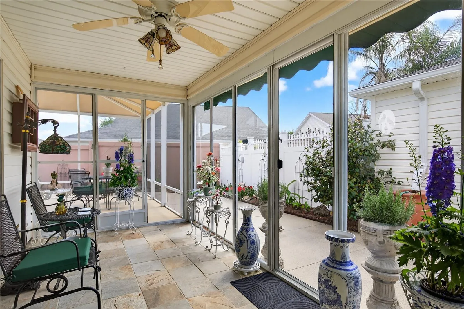 This beautiful property features a  glass-enclosed lanai, complete with  stylish slate tile floors, offering a serene space to relax and enjoy the outdoors. The lanai provides picturesque views of the inviting courtyard, which is beautifully enhanced by lush, vibrant tropical Florida landscaping.