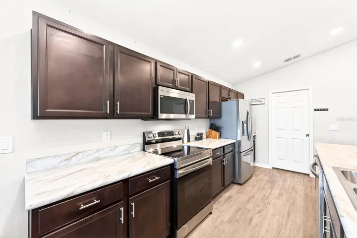 The Kitchen is designed with functionality in mind, offering an ABUNDANCE OF CABINETRY, marble-look laminate countertops, a WALK-IN PANTRY, and a breakfast bar.