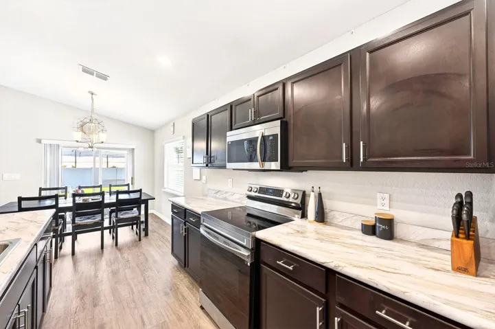 The Kitchen is designed with functionality in mind, offering an ABUNDANCE OF CABINETRY, marble-look laminate countertops, a WALK-IN PANTRY, and a breakfast bar.