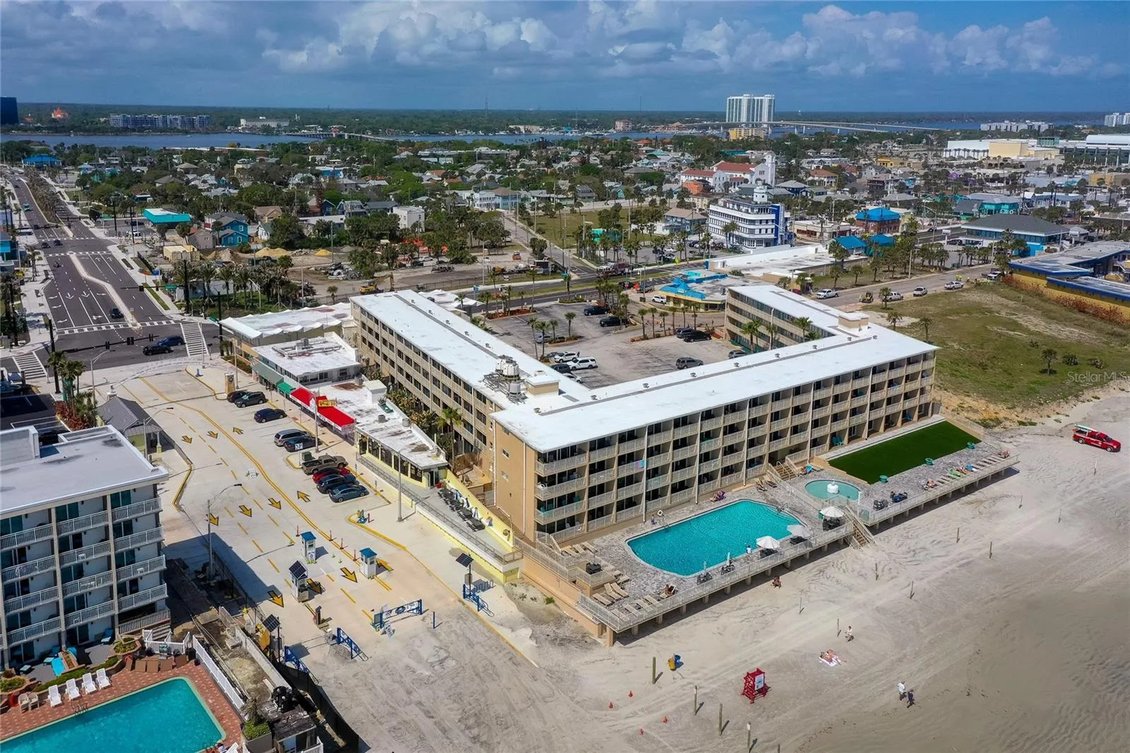 Oceanfront aerial highlights the building’s direct placement on the sand with resort-style pool areas and easy beach access.