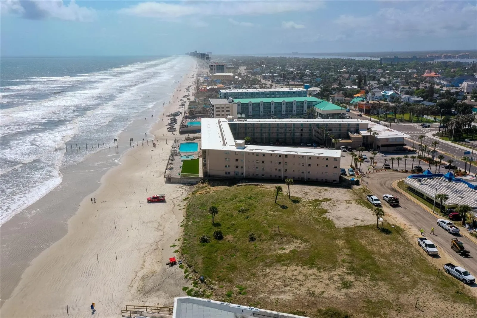 Sweeping coastline aerial emphasizes the property’s exceptional oceanfront setting along a wide stretch of sandy beach.