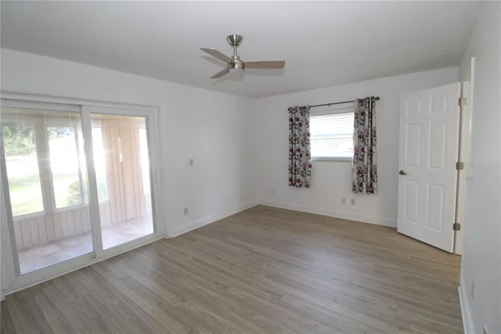 Bedroom with good natural light through the sliding glass doors.  Updated ceiling fan, beautiful flooring and fresh paint throughout.