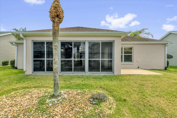 Rear view showcasing the spacious enclosed lanai and private outdoor setting—perfect for relaxing or entertaining.