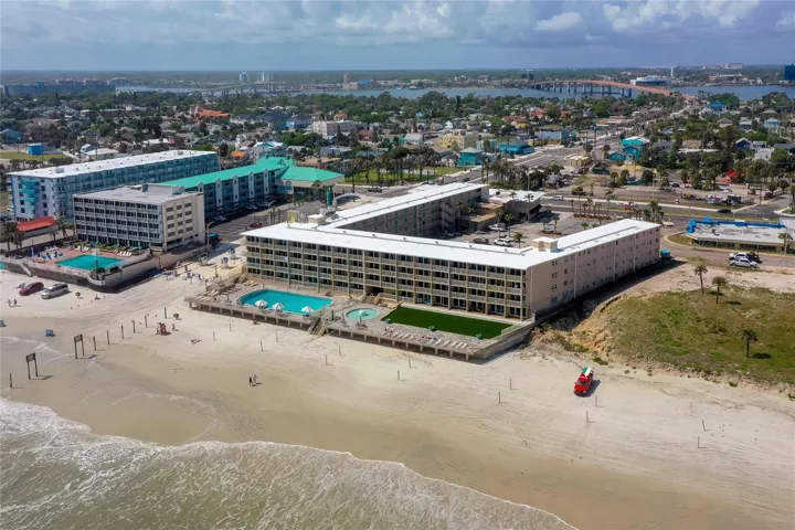 Wide aerial view captures the full beachfront footprint of the property, with direct access to the shoreline and on-site outdoor amenities. The setting offers a true oceanfront lifestyle in the heart of Daytona Beach.