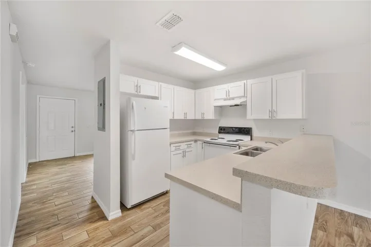To the well appointed updated kitchen, featuring a breakfast bar, dishwasher , fridge & range