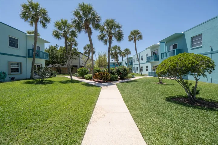 Community courtyard with palm trees, paved walkway, and landscaped grounds