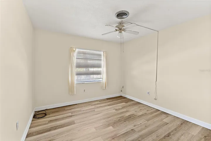 Guest Bedroom with wood-look LVP flooring, ceiling fan, and window — Ocean Park South condo