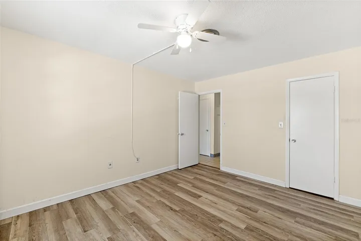 Primary Bedroom with wood-look LVP flooring, ceiling fan, and walk-in closet — Ocean Park South unit G20