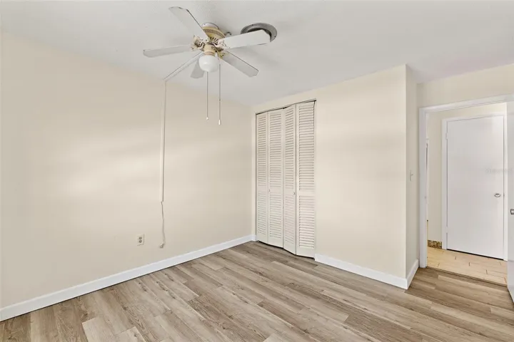 Guest Bedroom with louvered closet doors, LVP flooring, and ceiling fan — Cape Canaveral condo