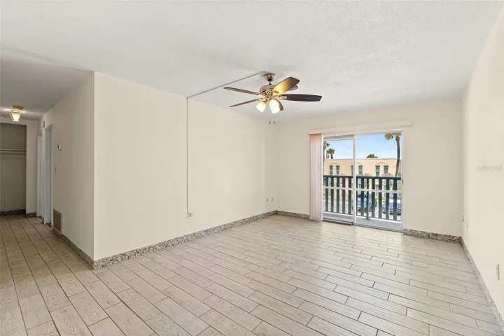 Living area with tile flooring, ceiling fan, balcony access