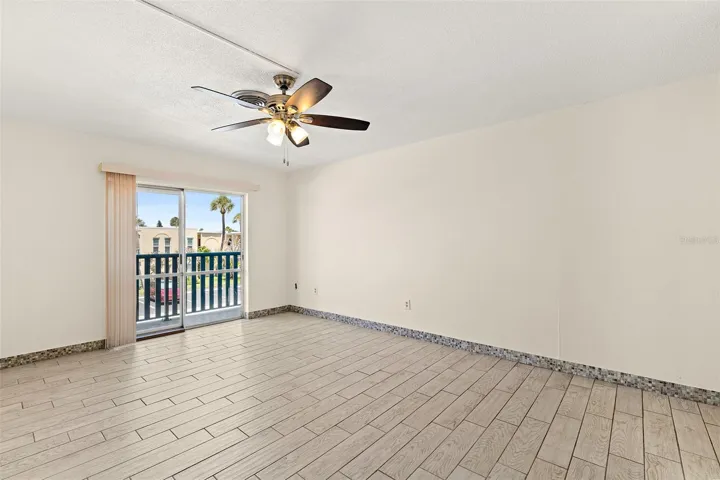 Living area with tile flooring, ceiling fan, and sliding glass door to balcony