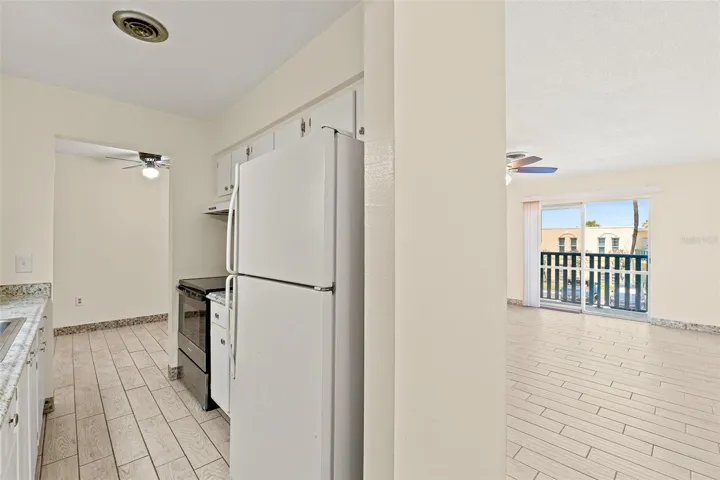 Kitchen and living area view with white refrigerator, electric range, and balcony