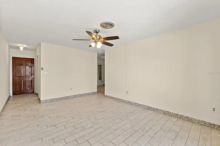 Living area with tile flooring, ceiling fan, wood front door