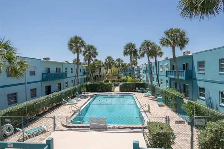 Aerial view of fenced community pool with lounge chairs — Ocean Park South condo