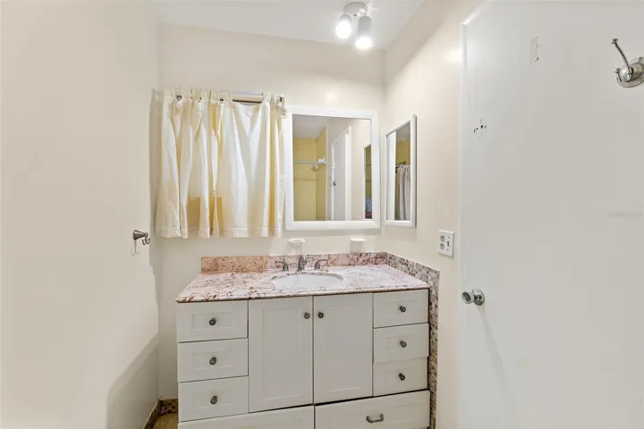 Bathroom vanity with white cabinetry, granite-look countertop, and single sink