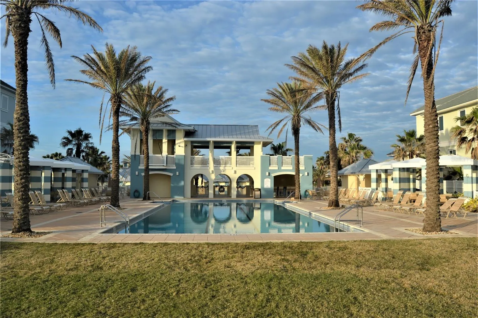Oceanside pool features lounge chairs, covered seating, hot tub.
