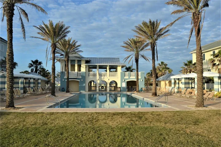 Oceanside pool features lounge chairs, covered seating, hot tub.