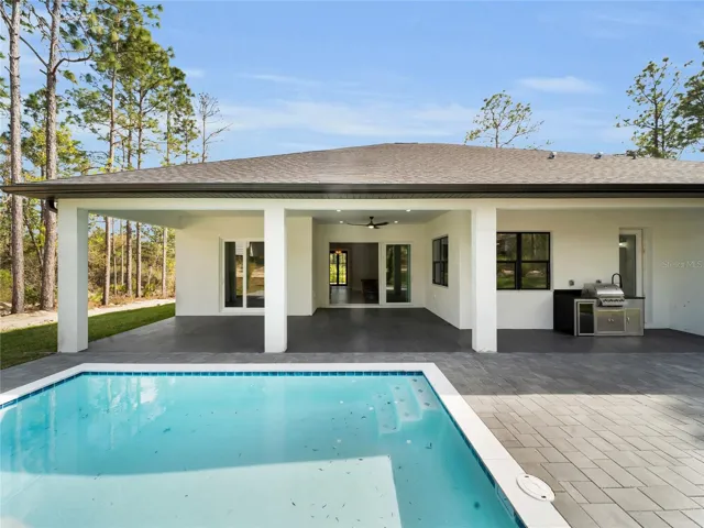 Pool area with covered lanai and outdoor kitchen