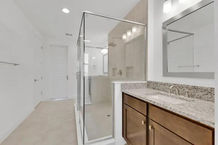 Primary Ensuite with split vanities. Privacy toilet to the left, and barn door leading into the Primary Suite