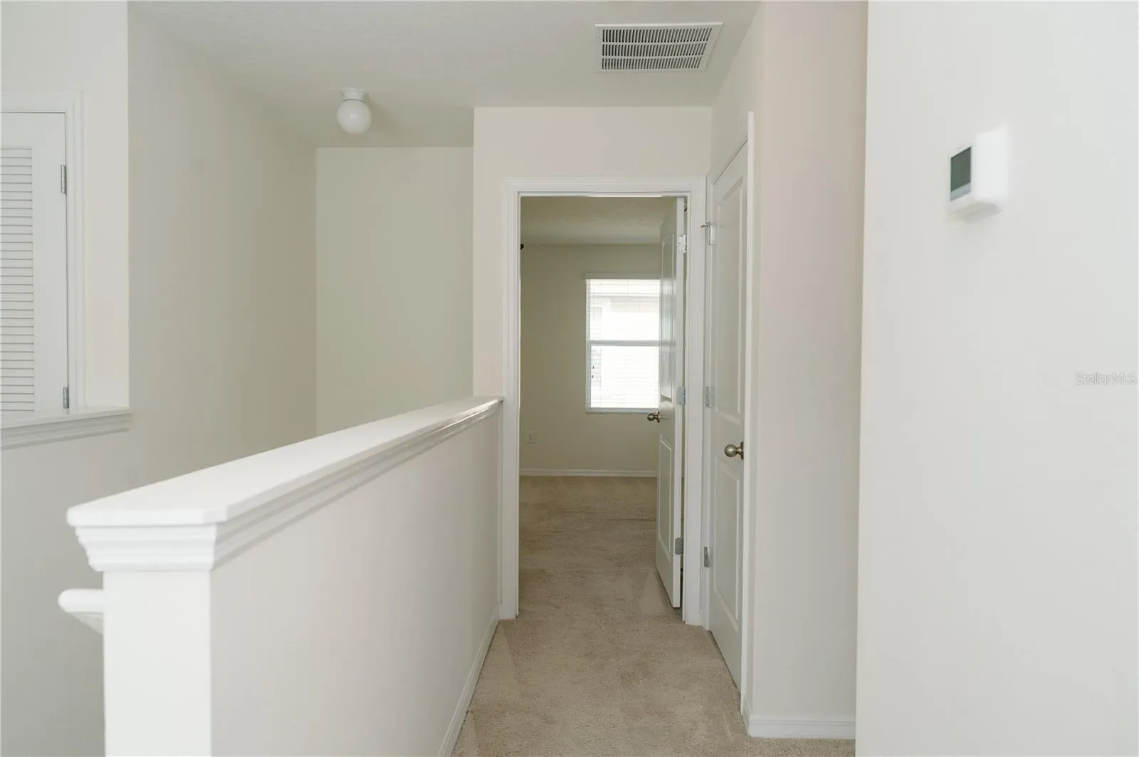 View from upper stairway landing looking towards the primary bedroom door and the hallway (right) to bathrrom, lanudry room and bedroom 3