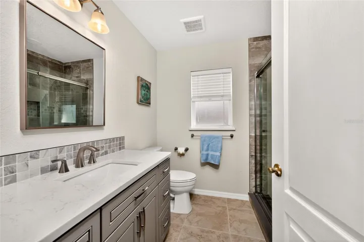 Guest bath has been updated with new vanity matching the kitchen cabinetry, quartz countertop, new mirror, and new lighting.