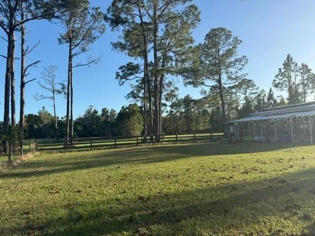 Side and view to back of property (past the rear fence behind pole barn is also part of this property).