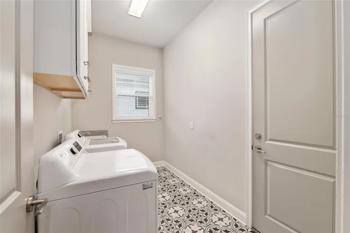 Spacious laundry room with upgraded tile, sink and cabinetry