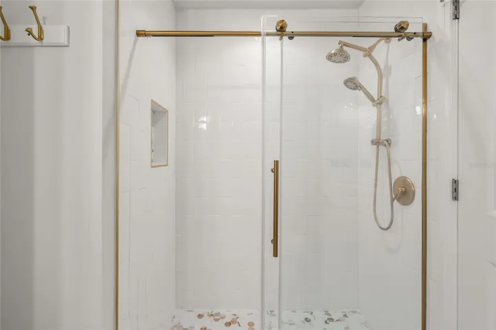 Tasteful frameless glass shower with gold accents.