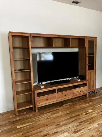 Wood entertainment center and large screen TV stays with house.