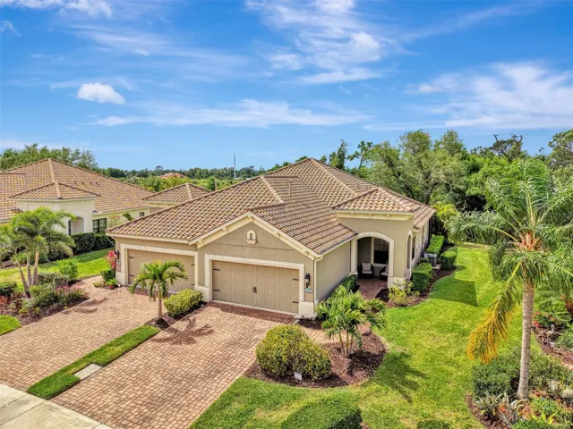 Paired villa in Boca Royale with paver driveway and tile roof. Tropical setting in North Englewood.