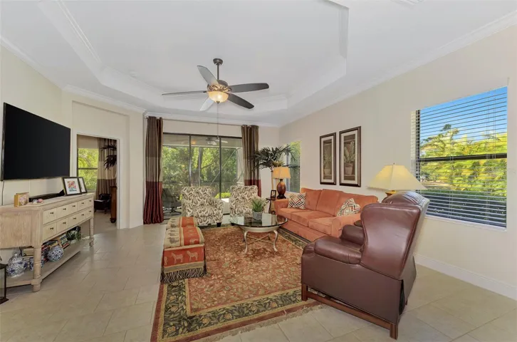 Living Room with Step-Ceiling and Crown Molding, Blinds, Sliders, Drapes, Ceiling fans, Screened lanai.