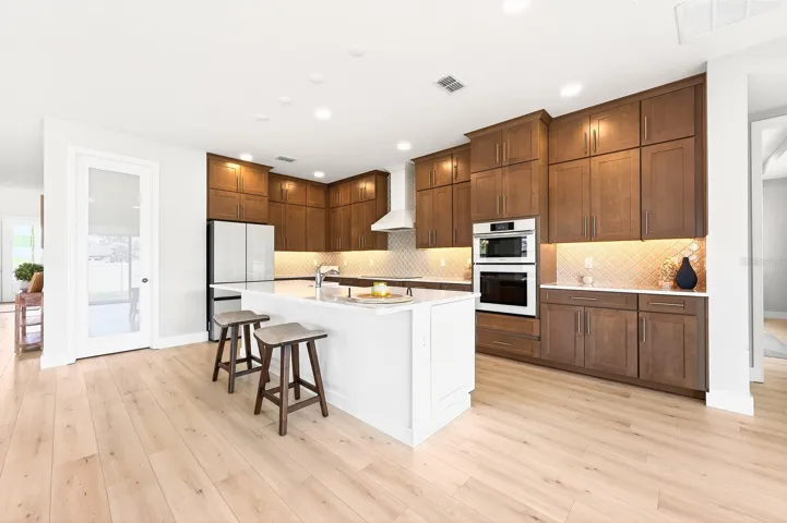 At the heart of the home is a gorgeous chef’s kitchen designed to impress, featuring QUARTZ COUNTERTOPS, rich cabinetry extending to the ceiling, soft-close features, under-cabinet lighting, built-in UPGRADED APPLIANCES, a tiled backsplash, pantry storage, and a large contrasting ISLAND with breakfast bar seating.