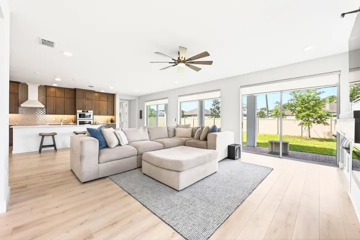 A wall of sliding glass doors open to the covered paver lanai and fully fenced backyard beyond.