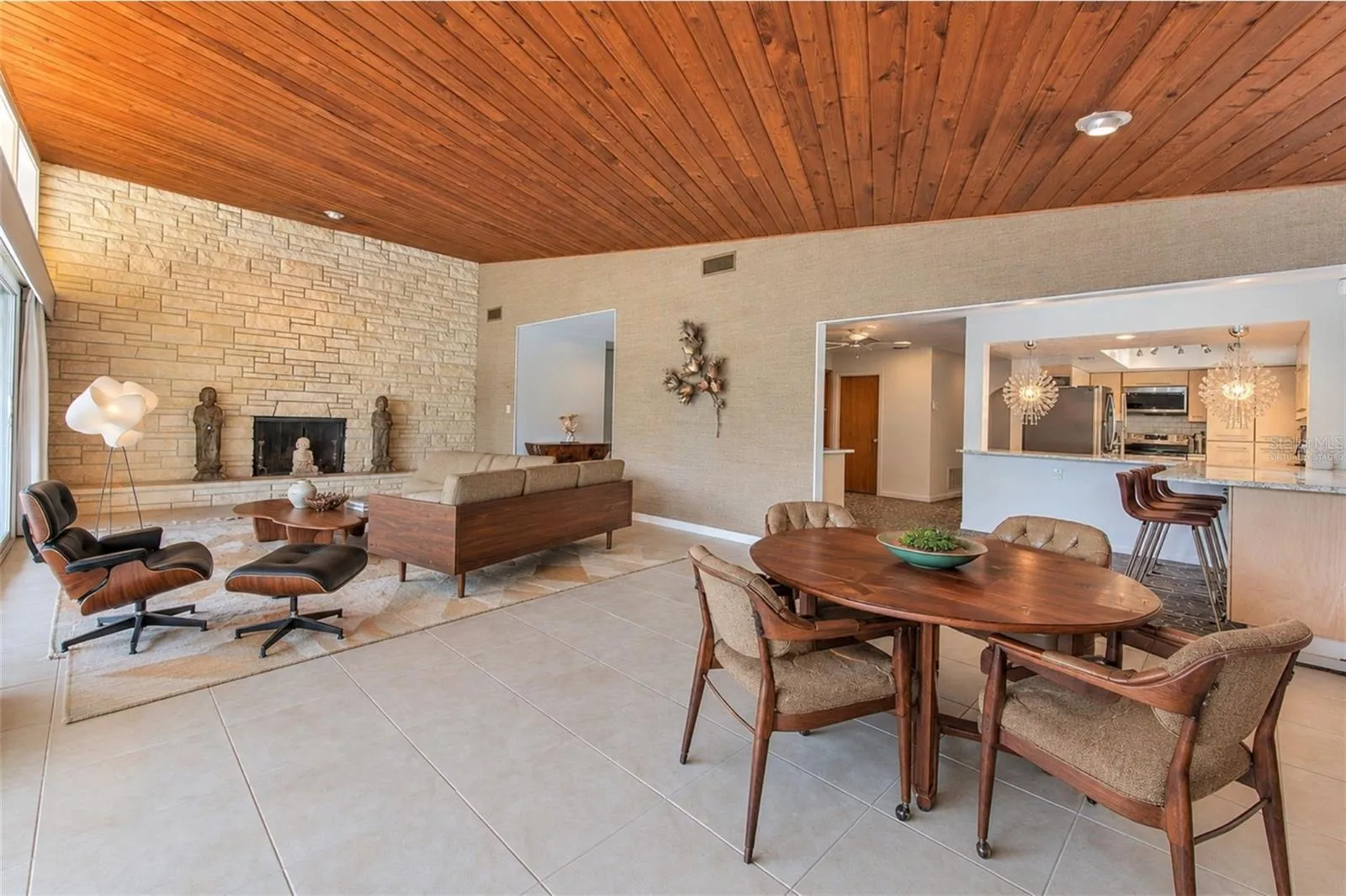 virtually staged -  Waterfront MCM living room, floor to ceiling glass slider doors, stone fireplace, tongue &amp; groove ceiling