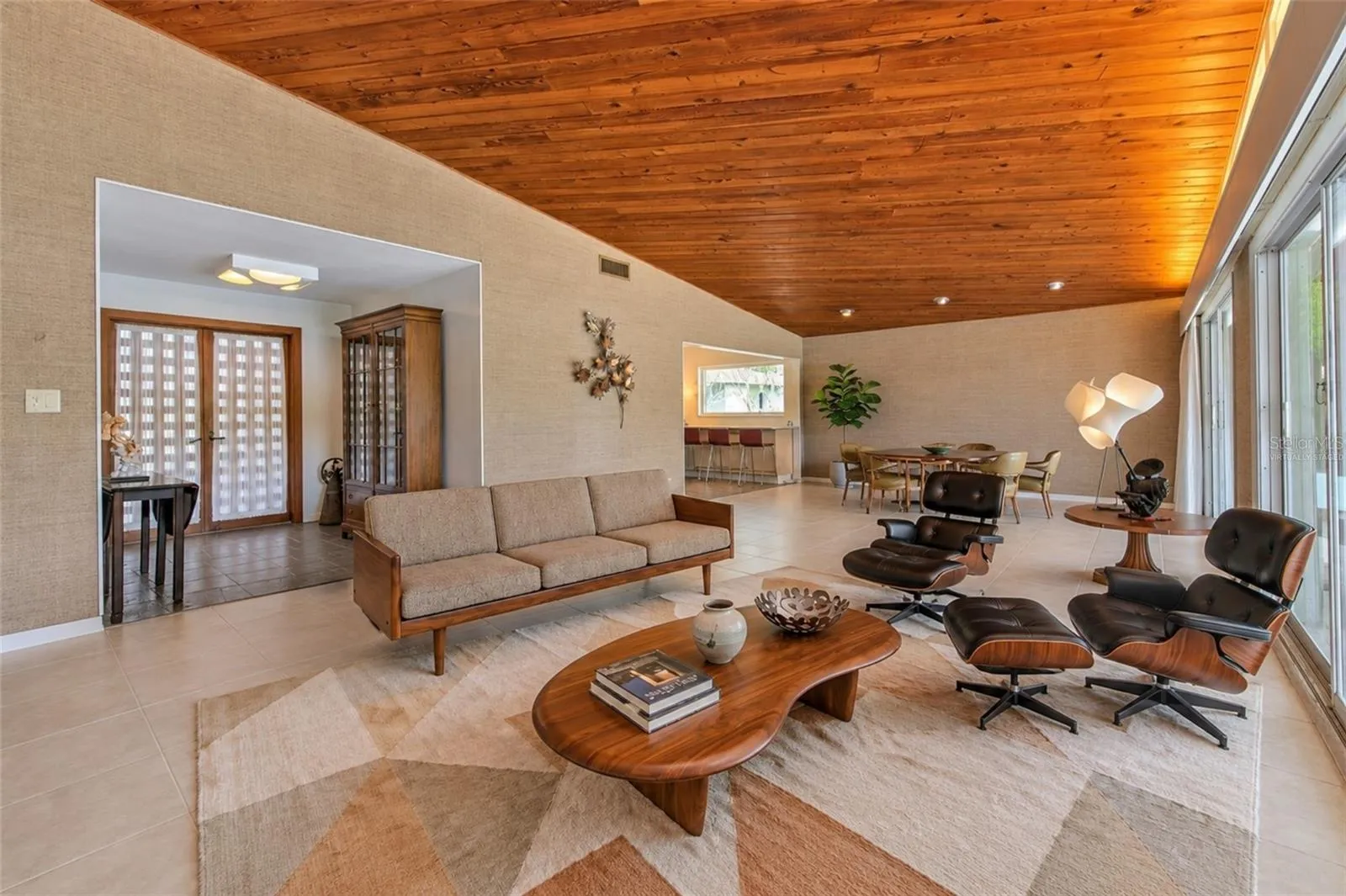 virtually staged -  Waterfront MCM living room, floor to ceiling glass slider doors, stone fireplace, tongue &amp; groove ceiling