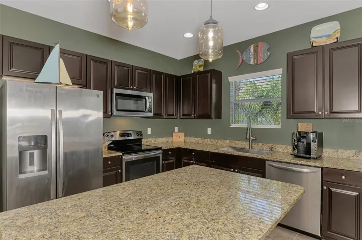 Modern Kitchen with raised panel doors, stainless steel appliances, undermount sink with premium faucet. Kitchen window tropical views outdoors.