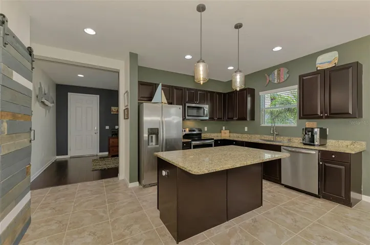 Modern Kitchen with stainless steel appliances, large undermount sink, granite counters, pendant lighting, tropical views.