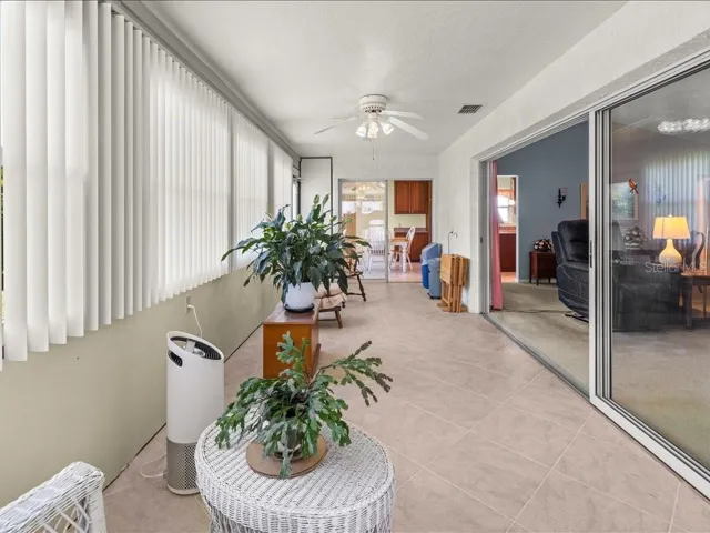 VIEW OF THE FLORIDA ROOM TOWARDS THE KITCHEN. OVERSIZED SLIDING DOOR LEADS TO THE LIVING ROOM.
