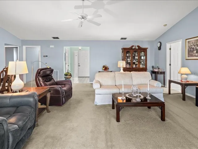 VIEW OF THE LIVING ROOM TOWARDS THE FOYER. THE PRIMARY BEDROOM IS ON THE RIGHT AND THE 2ND BEDROOM, LAUNDRY AND GUEST BATH ARE ACCESSIBLE TO THE LEFT.