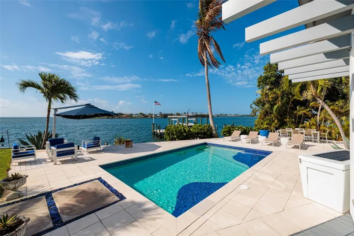 Resort-style waterfront pool terrace framed by dramatic sunset skies