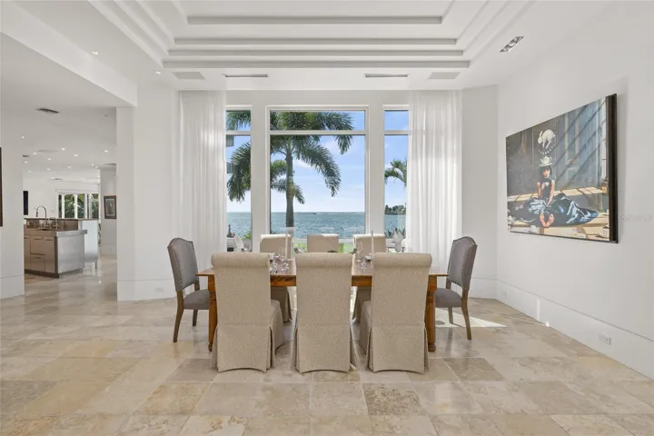 Elegant dining room with coffered ceilings, waterfront views, and natural light